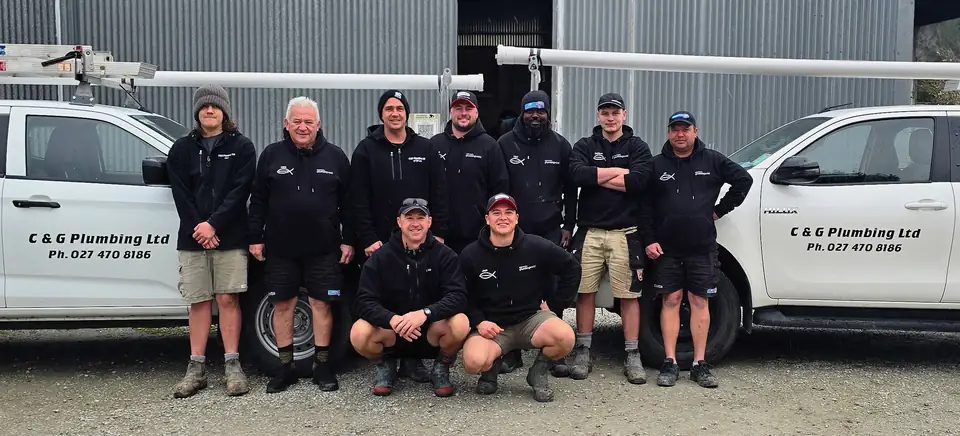 The C & G Plumbing team standing in front of their work utes in Gisborne