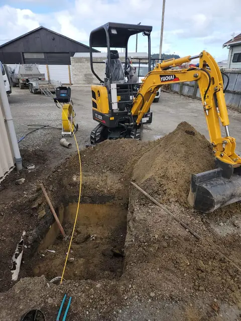 Mini digger in a deep excavation for commercial drainage work
