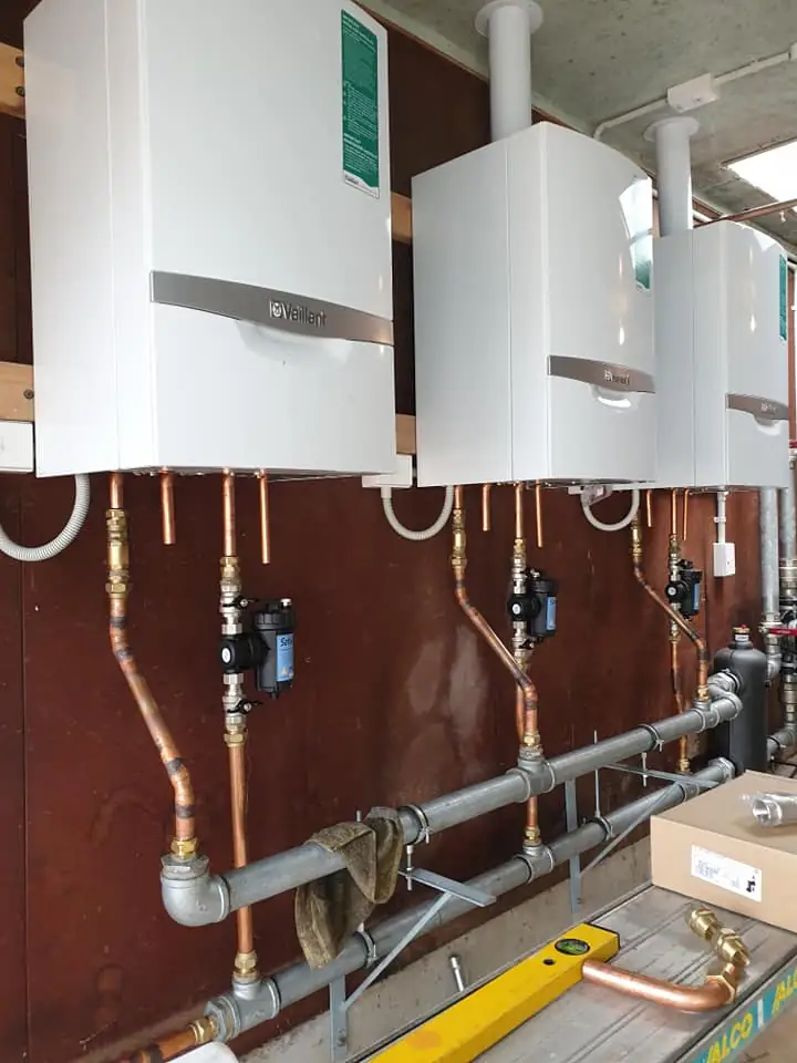 Bank of gas continuous flow hot water units with copper pipework in a commercial plant room