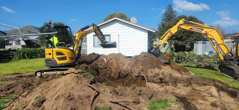 Two diggers excavating a drainage trench beside a Gisborne home