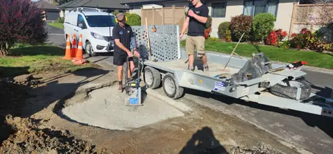 C & G Plumbing crew compacting ground after drainage work in a driveway