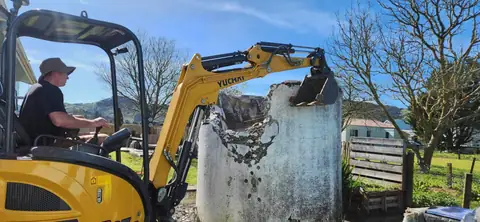 Digger lifting an old concrete septic tank out of the ground in Gisborne