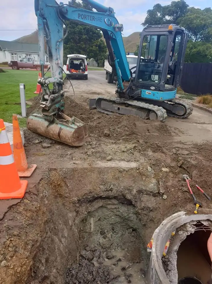 Excavator digging a roadside trench for a sewer connection